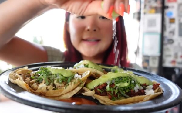 Rose Lee holds a plate of vegan tacos and pours lemon over them while exploring Mexico City’s plant-based scene