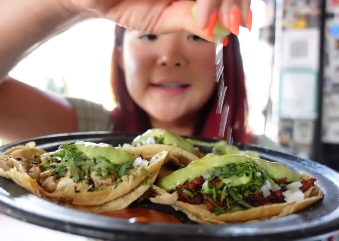 Rose Lee holds a plate of vegan tacos and pours lemon over them while exploring Mexico City’s plant-based scene