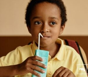 Photo shows a young boy in a school cafeteria drinking out of a carton. Sixty-seven percent of Americans agree that kids should have access to plant-based school meals and milk