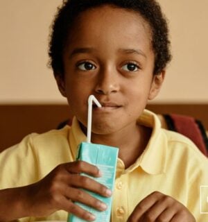 Photo shows a young boy in a school cafeteria drinking out of a carton. Sixty-seven percent of Americans agree that kids should have access to plant-based school meals and milk