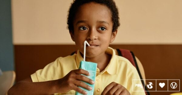 Photo shows a young boy in a school cafeteria drinking out of a carton. Sixty-seven percent of Americans agree that kids should have access to plant-based school meals and milk
