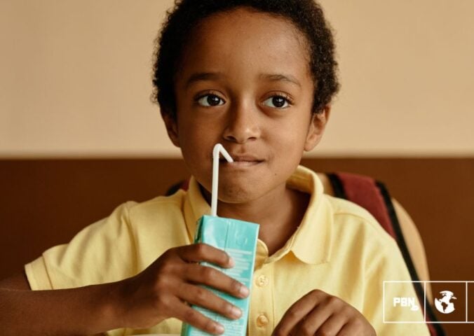 Photo shows a young boy in a school cafeteria drinking out of a carton. Sixty-seven percent of Americans agree that kids should have access to plant-based school meals and milk