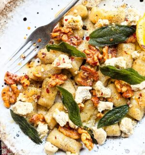 a plate of homemade gnocchi with sage, walnuts, and vegan blue cheese
