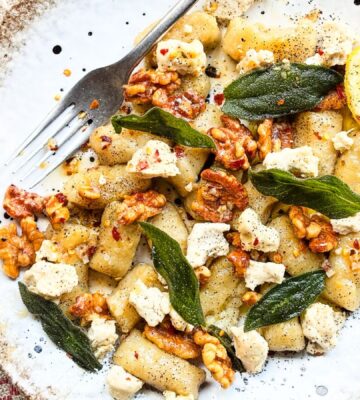 a plate of homemade gnocchi with sage, walnuts, and vegan blue cheese