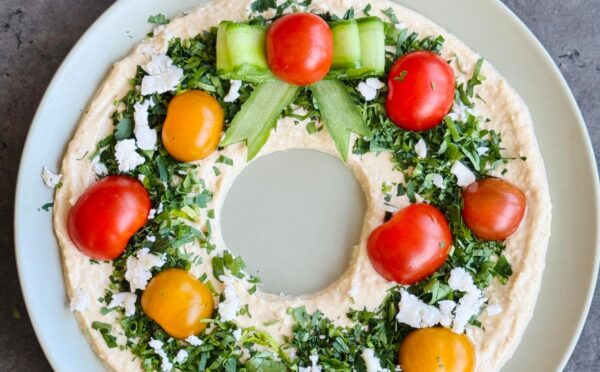 a vegan hummus Christmas wreath with parsley, cherry tomatoes, and cucumber