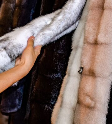 Photo shows someone feeling the texture of a fur coat on a rack in a store. Is wearing fur really back in fashion?