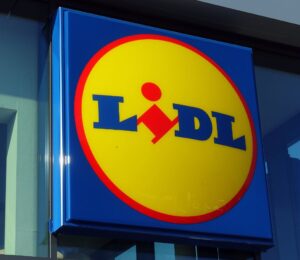 Photo shows the distinctive Lidl sign in red, yellow, and blue above a store entrance. Lidl has called on the UK government to introduce mandatory plant-based sales targets and plant-based sales reporting