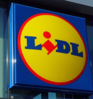 Photo shows the distinctive Lidl sign in red, yellow, and blue above a store entrance. Lidl has called on the UK government to introduce mandatory plant-based sales targets and plant-based sales reporting