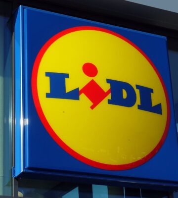 Photo shows the distinctive Lidl sign in red, yellow, and blue above a store entrance. Lidl has called on the UK government to introduce mandatory plant-based sales targets and plant-based sales reporting