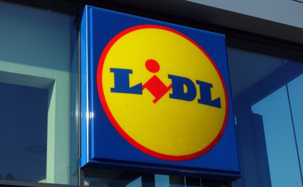 Photo shows the distinctive Lidl sign in red, yellow, and blue above a store entrance. Lidl has called on the UK government to introduce mandatory plant-based sales targets and plant-based sales reporting