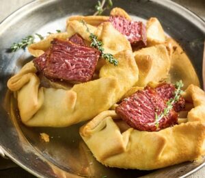 a picture of a plate of vegan mini flank galettes with caramelized onion and pear, drizzled with balsamic glaze