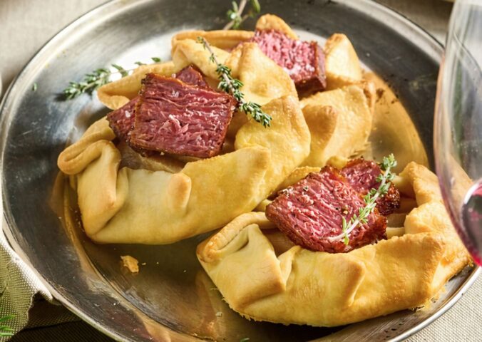 a picture of a plate of vegan mini flank galettes with caramelized onion and pear, drizzled with balsamic glaze