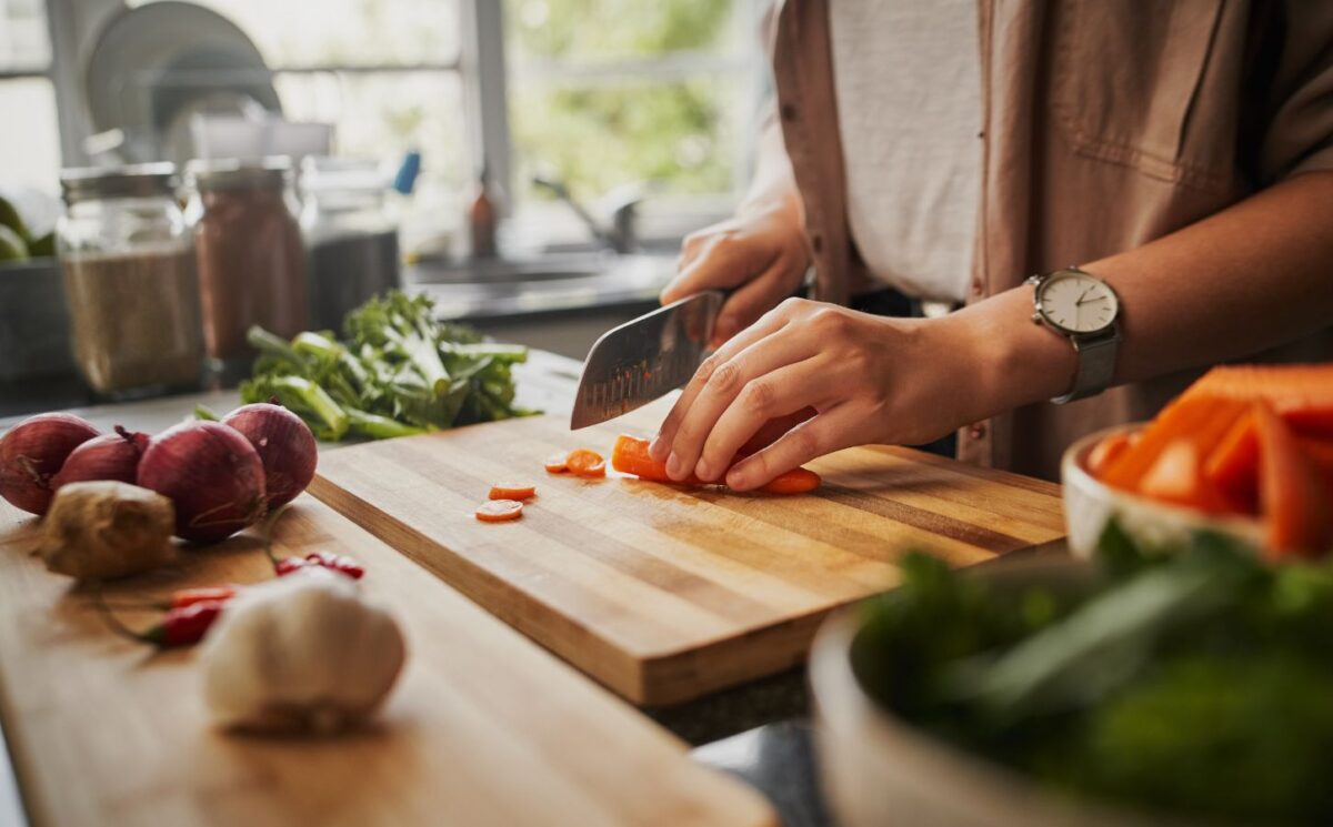 Photo shows a woman chopping fresh vegetables in a home kitchen. A new study has found that plant-based diets could help to prevent and reverse a specific type of heart disease, CMD, in hypertension patients