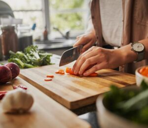Photo shows a woman chopping fresh vegetables in a home kitchen. A new study has found that plant-based diets could help to prevent and reverse a specific type of heart disease, CMD, in hypertension patients
