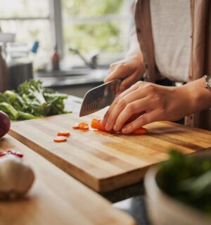 Photo shows a woman chopping fresh vegetables in a home kitchen. A new study has found that plant-based diets could help to prevent and reverse a specific type of heart disease, CMD, in hypertension patients