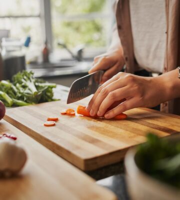 Photo shows a woman chopping fresh vegetables in a home kitchen. A new study has found that plant-based diets could help to prevent and reverse a specific type of heart disease, CMD, in hypertension patients