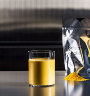Photo shows a pouch of Solein, a vegan microbial protein by Solar Foods, alongside a small pile of the powdered version and a vibrant yellow drink made of the same