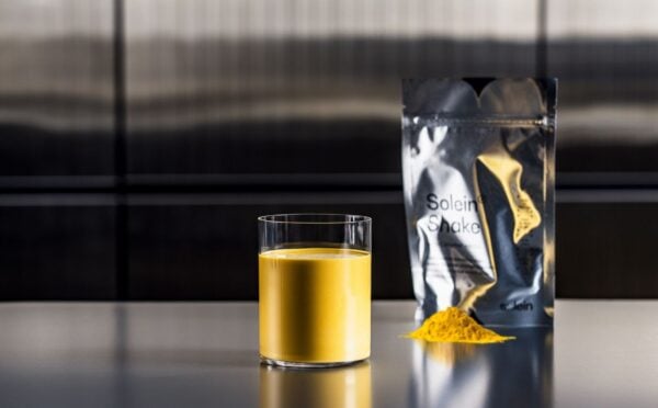 Photo shows a pouch of Solein, a vegan microbial protein by Solar Foods, alongside a small pile of the powdered version and a vibrant yellow drink made of the same