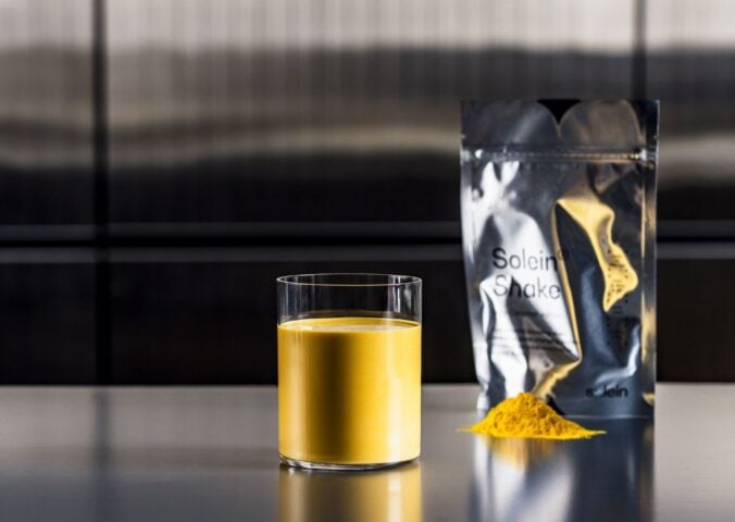 Photo shows a pouch of Solein, a vegan microbial protein by Solar Foods, alongside a small pile of the powdered version and a vibrant yellow drink made of the same