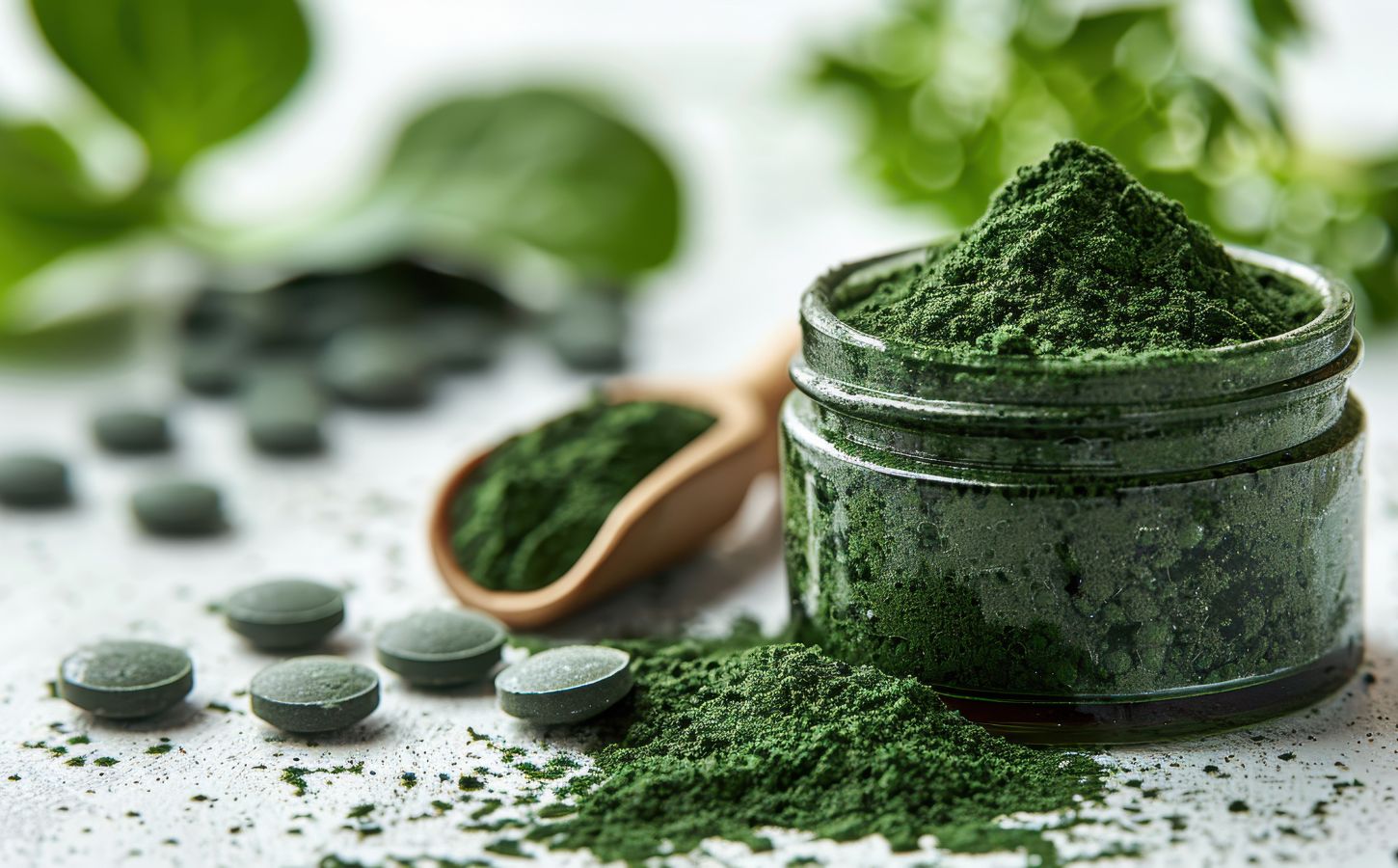 Close-up of green spirulina powder in a jar with tablets and a wooden spoon on a white surface, to showcase the dangers of spirulina