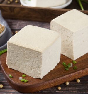 Two blocks of fresh tofu on a wooden cutting board, to illustrate the cancer-protective effects of soy