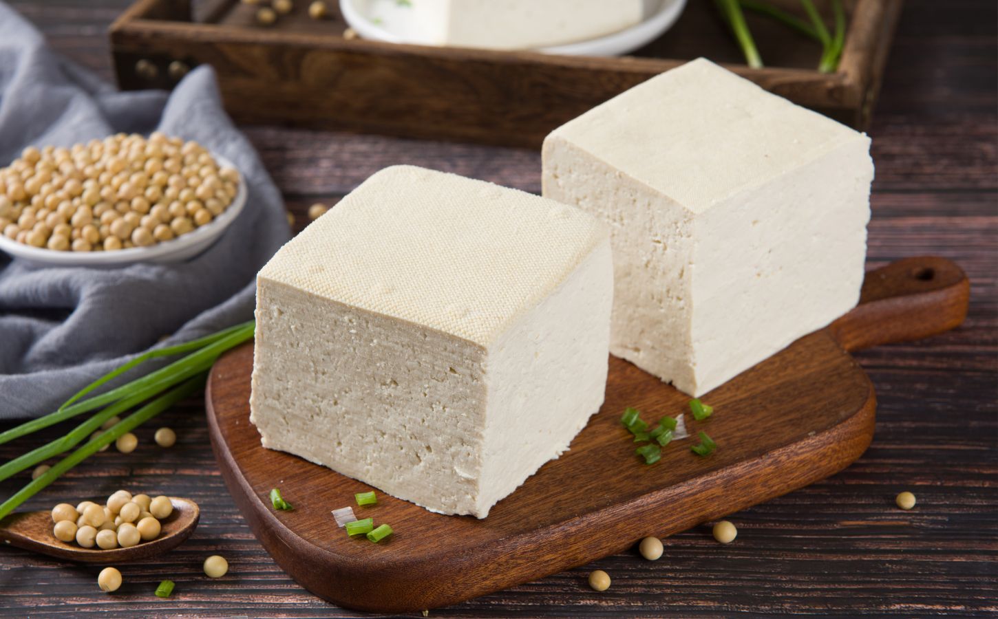 Two blocks of fresh tofu on a wooden cutting board, to illustrate the cancer-protective effects of soy