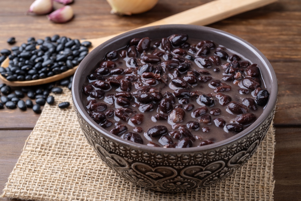Cooked black beans in a bowl set on a wooden table to illustrate the health benefits of black beans
