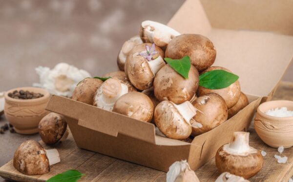Cremini mushrooms in a box to illustrate the Mushrooms and green onions on bread to illustrate the health benefits of mushrooms