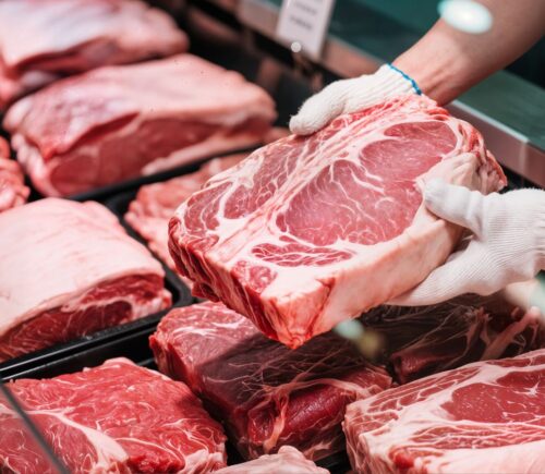 A display of raw red meat cuts in a butcher counter, illustrating the scary truth about eating meat.