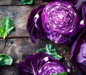 Three heads of purple cabbage on a rustic wooden table, highlighting the health benefits of purple cabbage