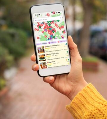 Photo shows someone's hand as they hold up a smartphone with the HappyCow app open on it. The platform recently named Asante, Barcelona, as the best vegan restaurant of 2025