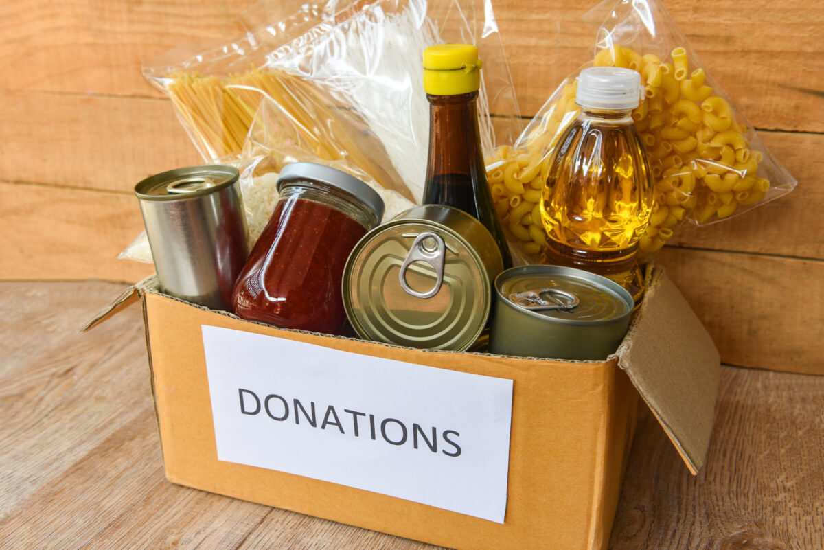 Photo shows a cardboard box full of shelf-stable food items and labelled "donations"