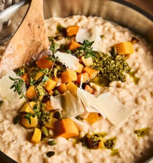 a pan of butternut squash risotto with cognac, pumpkin seed pesto, and fried thyme blossom