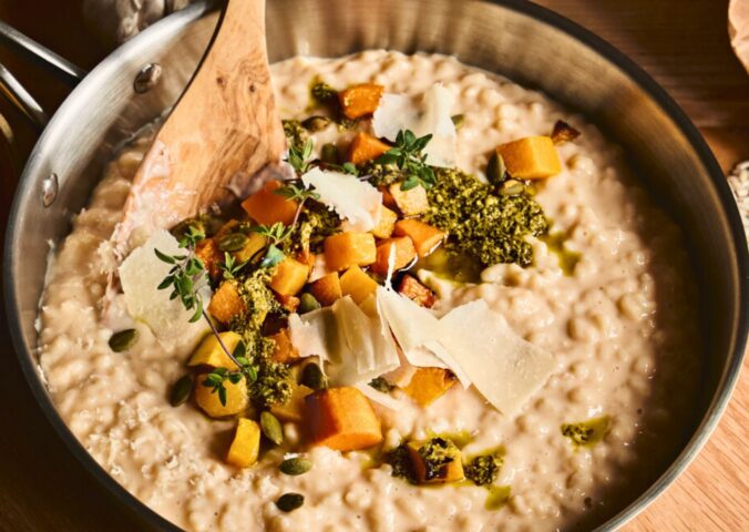 a pan of butternut squash risotto with cognac, pumpkin seed pesto, and fried thyme blossom