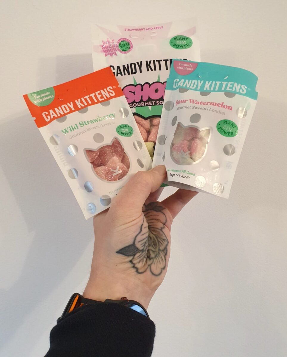 Photo shows a person's hand holding up three different varieties of Candy Kittens against a white background