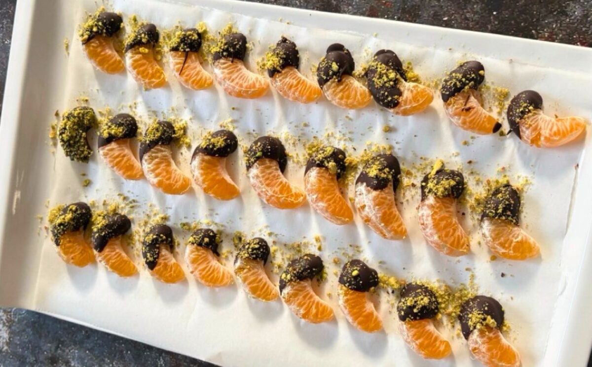 vegan chocolate mandarins with one half covered in chocolate and pistachio