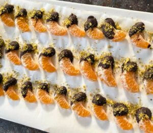 vegan chocolate mandarins with one half covered in chocolate and pistachio