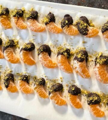 vegan chocolate mandarins with one half covered in chocolate and pistachio
