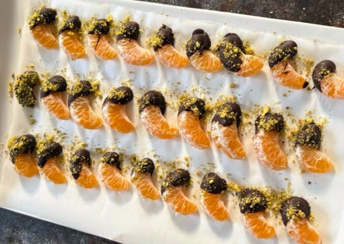 vegan chocolate mandarins with one half covered in chocolate and pistachio