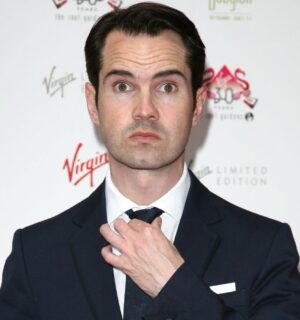 Photo shows Jimmy Carr straightening his tie and looking at the camera at an event in 2016
