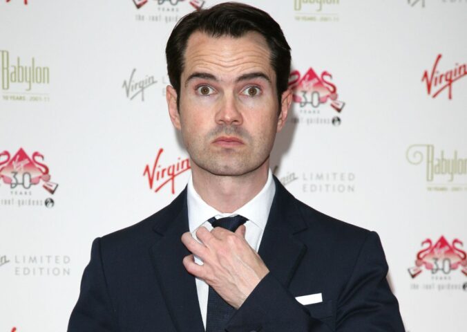 Photo shows Jimmy Carr straightening his tie and looking at the camera at an event in 2016