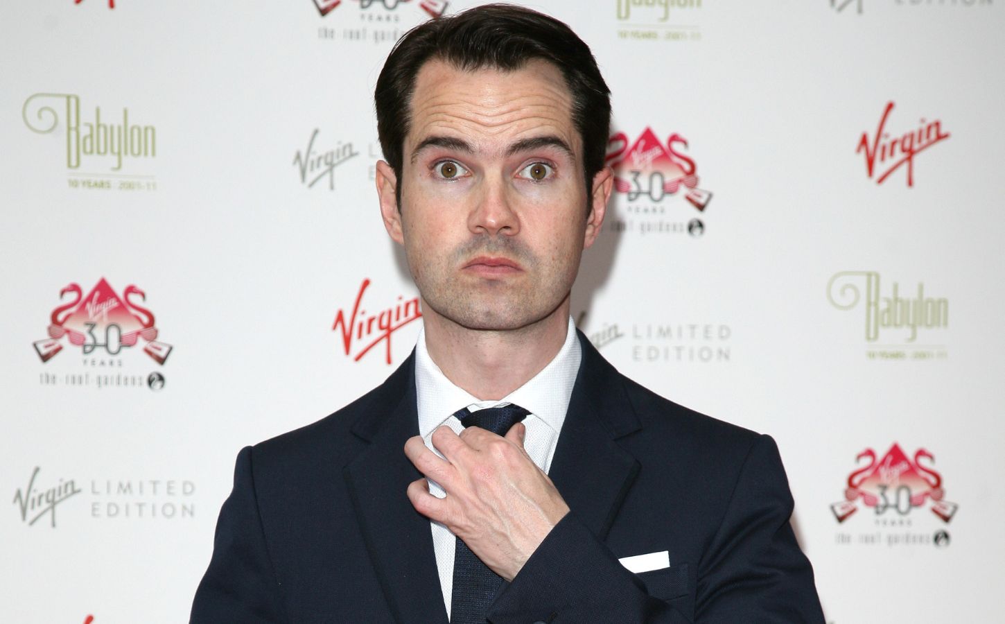Photo shows Jimmy Carr straightening his tie and looking at the camera at an event in 2016
