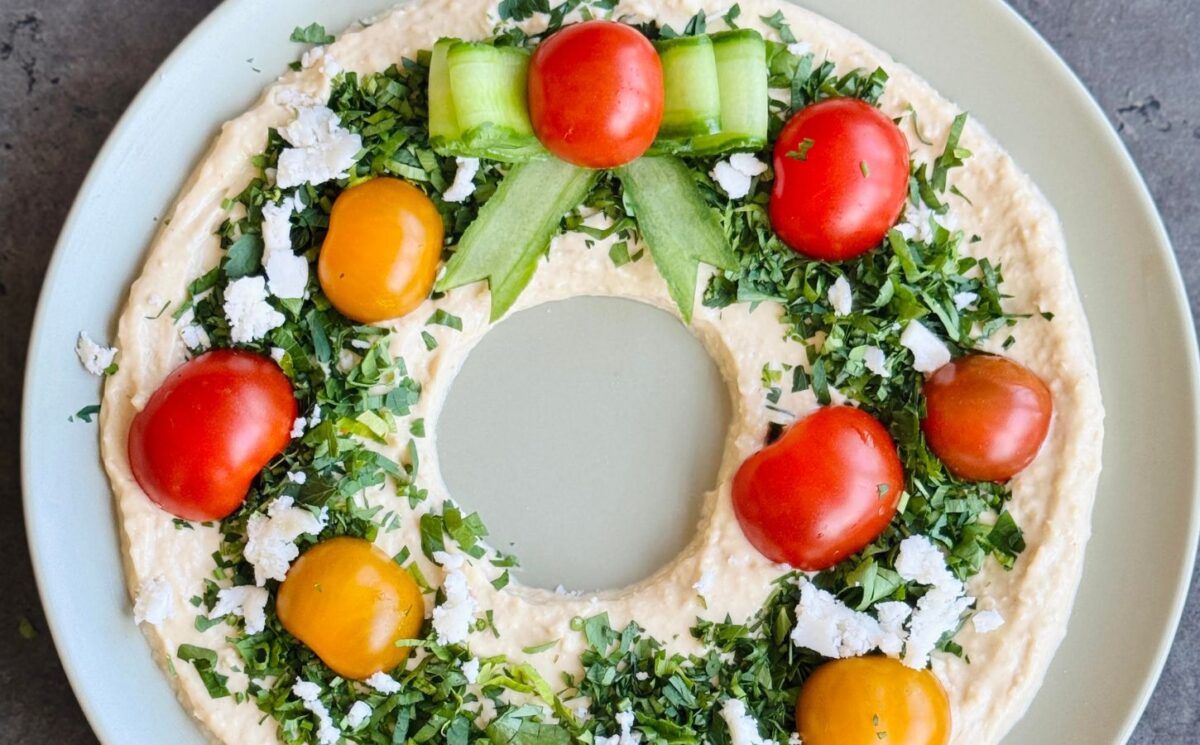 a vegan hummus Christmas wreath with parsley, cherry tomatoes, and cucumber for vegan Christmas continued
