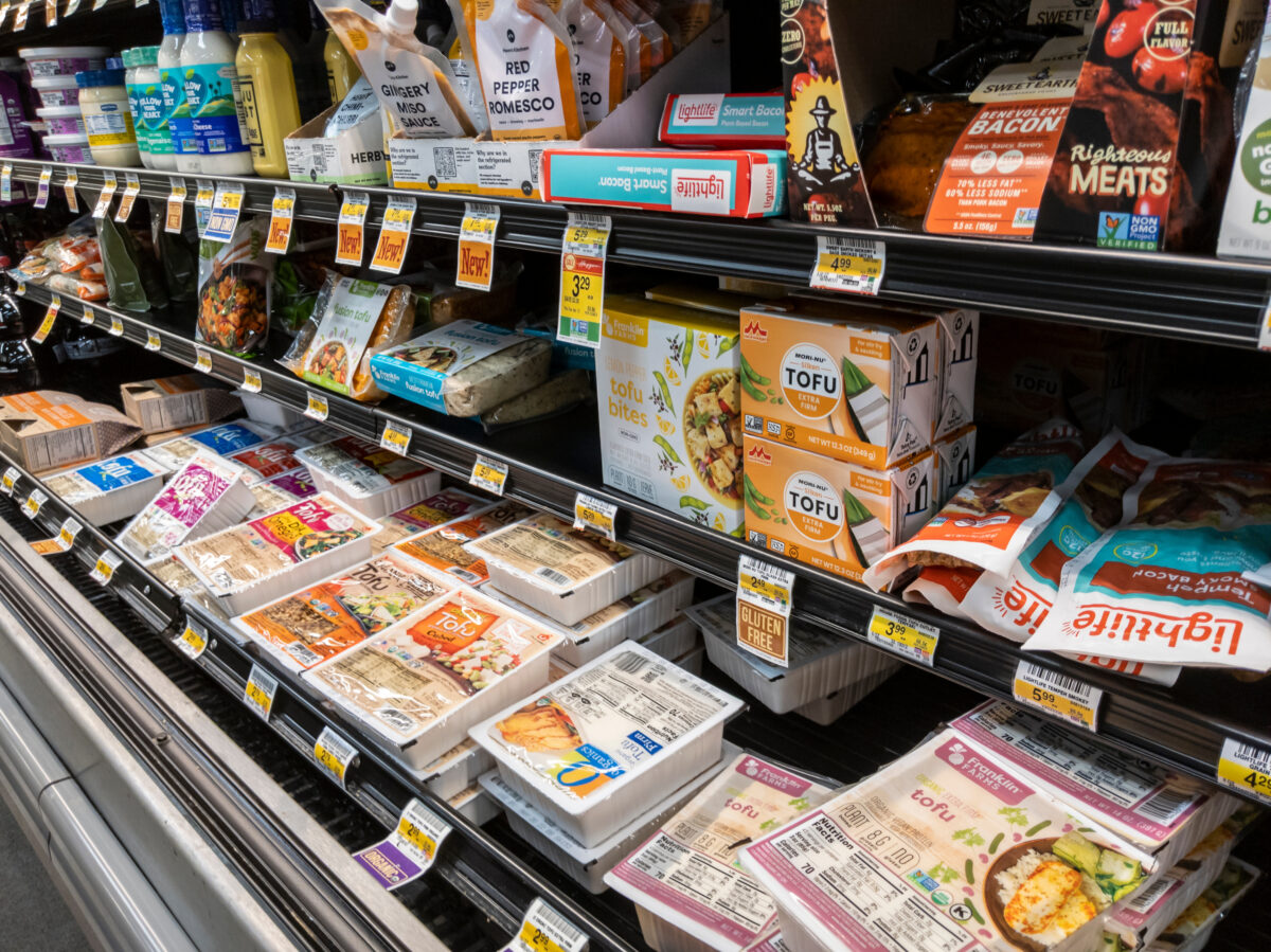Photo shows the refrigerated section of a supermarket, including a selection of plant-based meats and other products. A group of investors has called on major companies to divest from animal products to save the food system