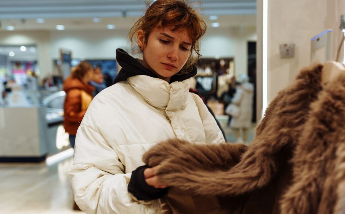 Photo shows a young woman looking at a fur coat in a department store. Rick Owens just became the latest luxury fashion brand to implement a fur ban