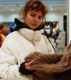 Photo shows a young woman looking at a fur coat in a department store. Rick Owens just became the latest luxury fashion brand to implement a fur ban