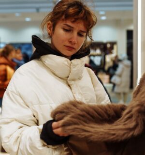 Photo shows a young woman looking at a fur coat in a department store. Rick Owens just became the latest luxury fashion brand to implement a fur ban