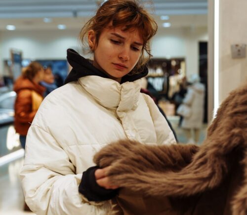 Photo shows a young woman looking at a fur coat in a department store. Rick Owens just became the latest luxury fashion brand to implement a fur ban