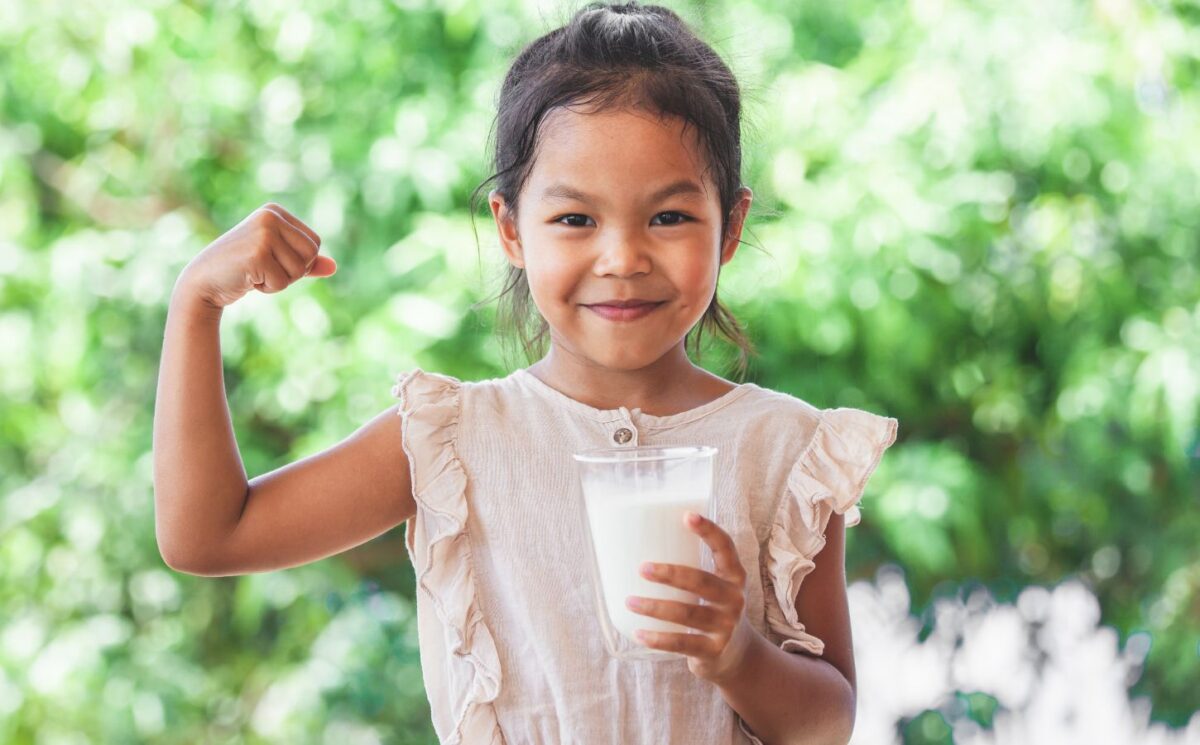 Photo shows a child flexing her bicep and holding a glass of milk. The US Senate just passed a bill that gives children access to plant-based milk in school