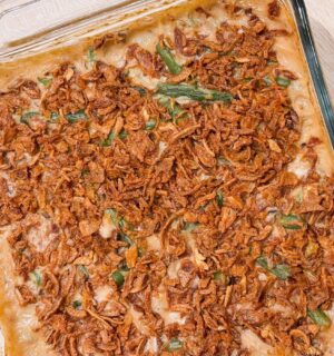 a dish of vegan parmesan bacon green bean casserole with mushroom soup and French-fried onions